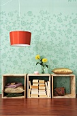 Wooden boxes with stacked books and orange hanging lamp in front of floral wall paper