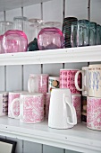 Mugs and glasses on white-painted shelves
