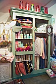 Shop im Shabbylook mit bemaltem Kleiderschrank ohne Türen und Blick auf Verkaufsware