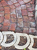 Curved, hollow concrete pavers edging a section uneven brick pavers