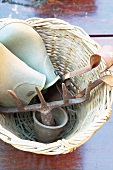 Basket with works clogs and old garden tools on a wooden table