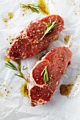 Two Raw Steaks with Marinade and Rosemary on Butcher's Paper