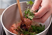 Preparing prawn sauce: add herbs to prawn shells