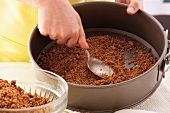 Spreading biscuit mixture on base of a loose-bottomed cake tin