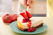 Serving California cheesecake with sour cream icing with strawberries