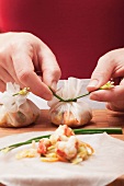 Tying stuffed rice paper packages together with chives