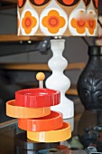 Cake stand with colourful plastic dishes in front of 70s lamp