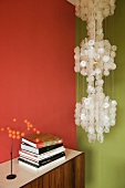 Pendant lamp with mother-of-pearl discs in corner of living room with two different coloured walls