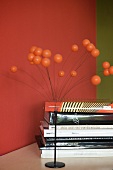 70s-style ornament with metal base and spray of spheres next to stack of books against red-painted wall