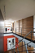 Gallery in house with open-plan stairwell and view of coloured wall on lower floor