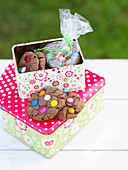 Cookies decorated with colourful chocolate beans in a biscuit tin
