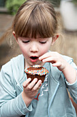 A little girl eating a chocolate cupcake