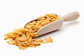 Cornflakes on wooden scoop against a white background