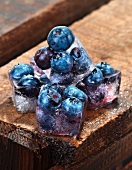 Ice cubes with blueberries on a wooden table