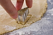 Hand cutting out Christmas tree-shaped cookies