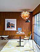 Desk with two chairs in front of large window in wood-panelled office