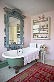 Old-fashioned bathroom in the 'Shabby' look with free standing bathtub, antique mirror and colorful carpet on plank flooring