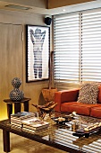 A corner of a living room featuring a African objet d'art on a wooden stool and a coffee table in front of a modern leather sofa