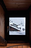 View of snowy roofscape through stairwell window