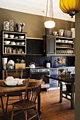 Olive green kitchen with antique furniture, art noveau ceiling lamp and a collection of black and white vases on the kitchen shelves