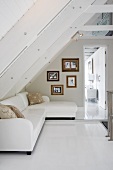 Elegant white sofa and framed photos on wall below open attic roof structure