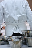 A chef and stainless steel bowls in a commercial kitchen