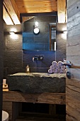 Wash basin hollowed out of stone block against wall with slate tiles