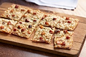 Flat Bread Pizza with Bacon; Cut Into Squares on a Cutting Board