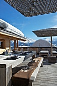 Gedeckter Tisch auf Holzterrasse einer Hütte in verschneiter Berglandschaft