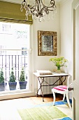 Table with metal frame and stone top in corner of room next to balcony door with view of potted plants