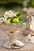 Silberne Schale gefüllt mit Schokoladeneier, Vergissmeinnicht Gartenjasmin und Schlehenblüten