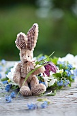 A toy rabbit with a snake's head flower in front of a wreath of forget-me-not
