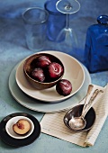 Plums, bowls, plates, spoons and glasses