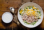 Ham salad with boiled eggs, cucumber and a bowl of sour cream