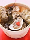Fresh oysters in a wooden basket, one opened with a heart on top