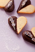 Heart-shaped biscuits decorated with chocolate icing and candied lavender flowers