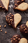 Heart-shaped biscuits decorated with chocolate icing and chopped nuts