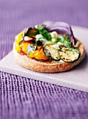 A mini pizza topped with peppers, courgettes and pine nuts