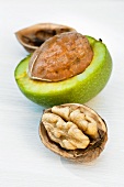 Two walnuts, half opened, with a green shell