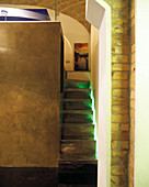 Narrow stairs with indirect lighting leading to gallery on cubic room-in-room installation below historic brick vault