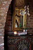 Potted orchid on antique console table and gilt-framed mirror on brick wall