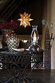 Candle lantern and urn on wrought iron side table in rustic foyer
