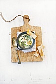 Fried egg with herbs in a pan with toasted bread sticks