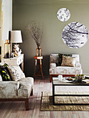 Armchairs, coffee table, console table and round prints on taupe walls of living room