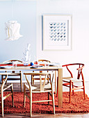 Tisch mit Designer-Stühlen, Hängelampe mit Papierschirm und Wollteppich in einem Esszimmer