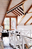 Workspace under sloping ceiling on gallery with white wooden balustrade