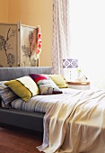 Screen with a floral pattern; in front a French bed with colorful decorative pillows