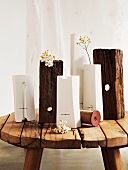 Verschiedene Vasen in Weiß und Holzstücke auf rustikalem Schemel