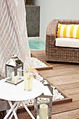 Lantern on modern side table and comfortable wicker armchair on modern wooden terrace