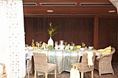 Table with a tablecloth in front of a dark wooden wall on a veranda